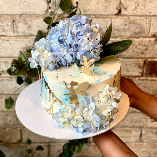 White cake with fairies and fresh blue flowers