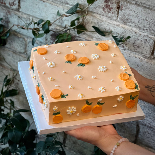 Square light orange cake with mandarins and white flowers design