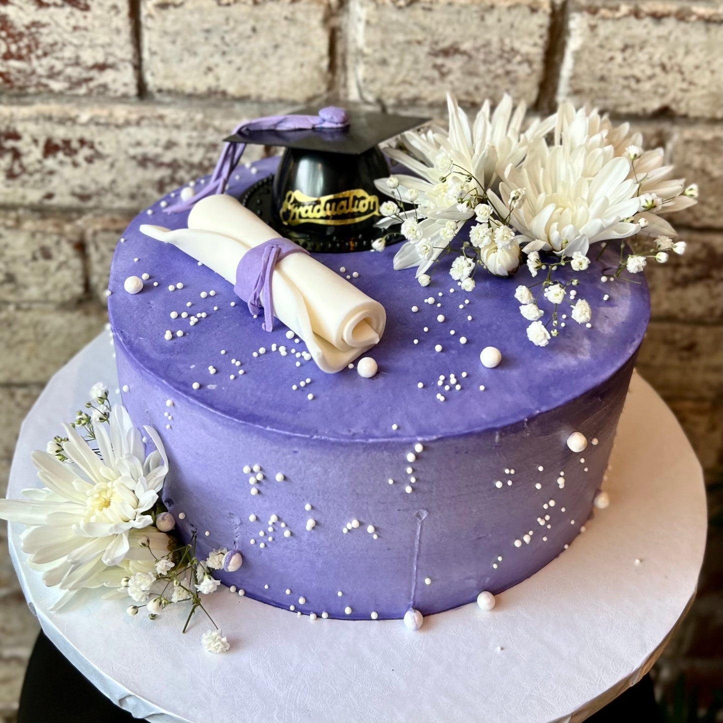 Purple graduation themed cake with fresh white flowers