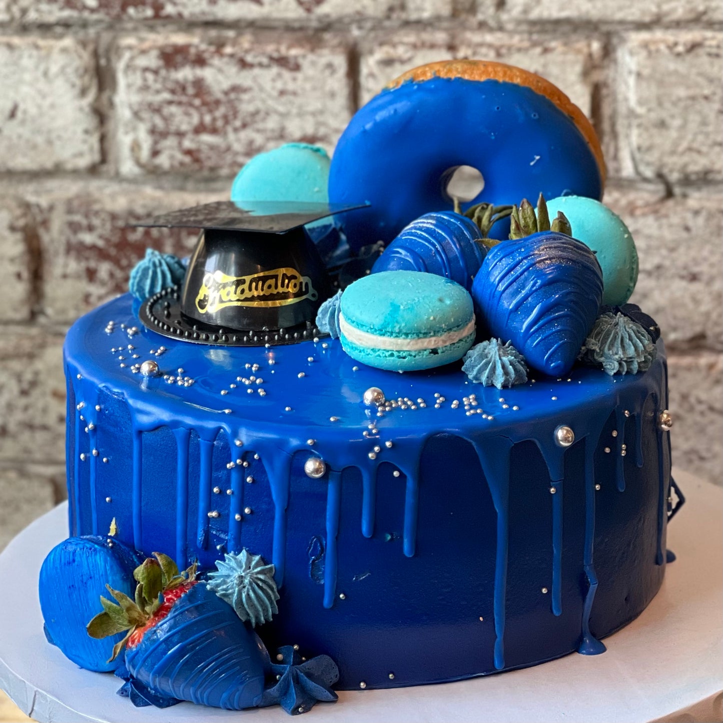 Blue graduation themed cake with donut, macarons and strawberries