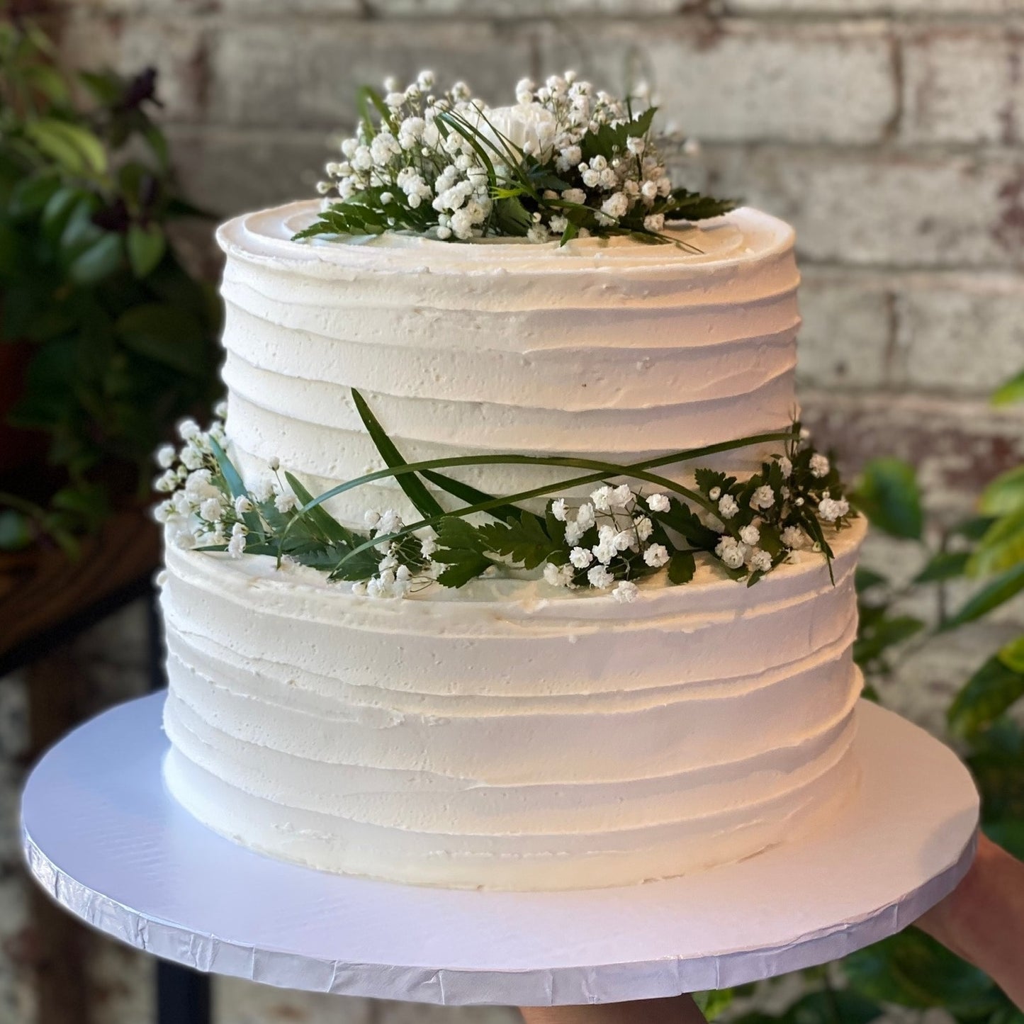 Two-tiered white cake with fresh baby's breath flowers