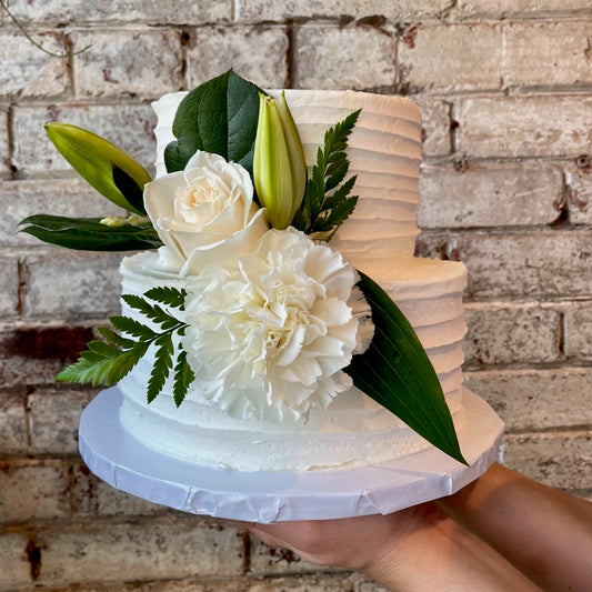 Two-tiered white cake with fresh flowers