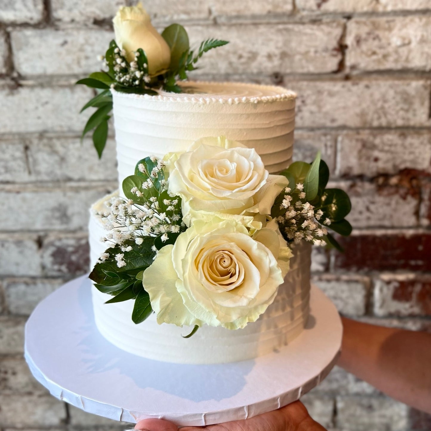 Two-tiered white cake with fresh flowers