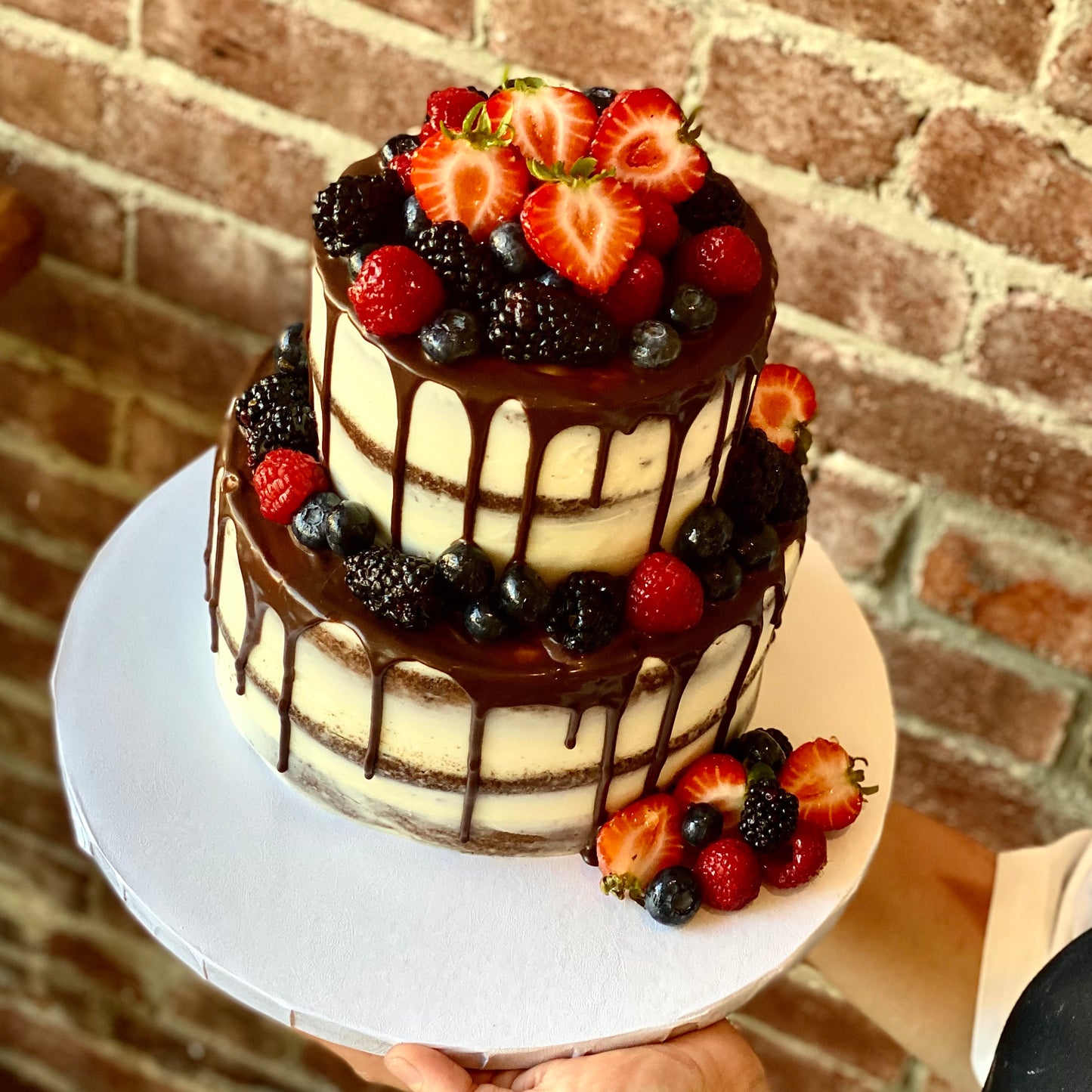 Two-tiered wedding cake with chocolate drip and fresh fruit