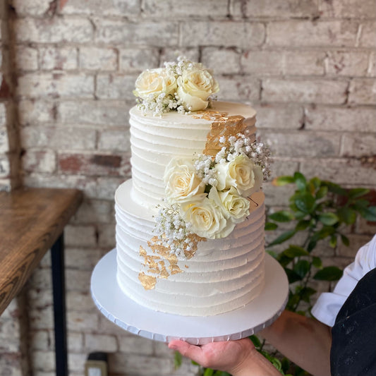 Two-tiered white wedding cake with fresh flowers