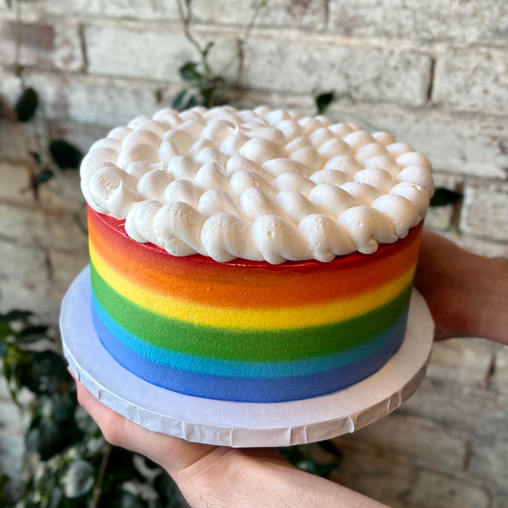 Cake with rainbow sides and white clouds on top