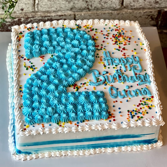 Square white cake with confetti and blue number two