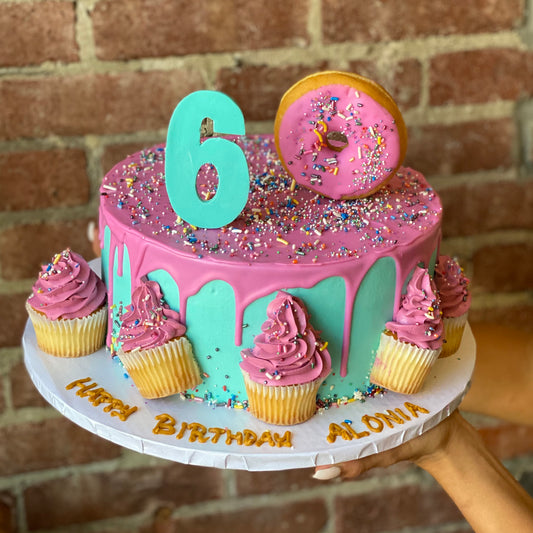 Teal coloured with pink drip, sprinkles and a donut
