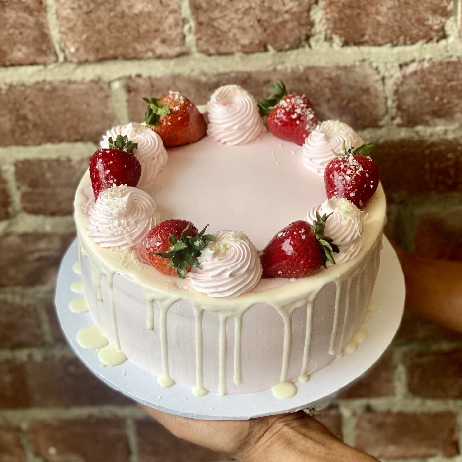 Pink cake with vanilla drip and chocolate strawberries