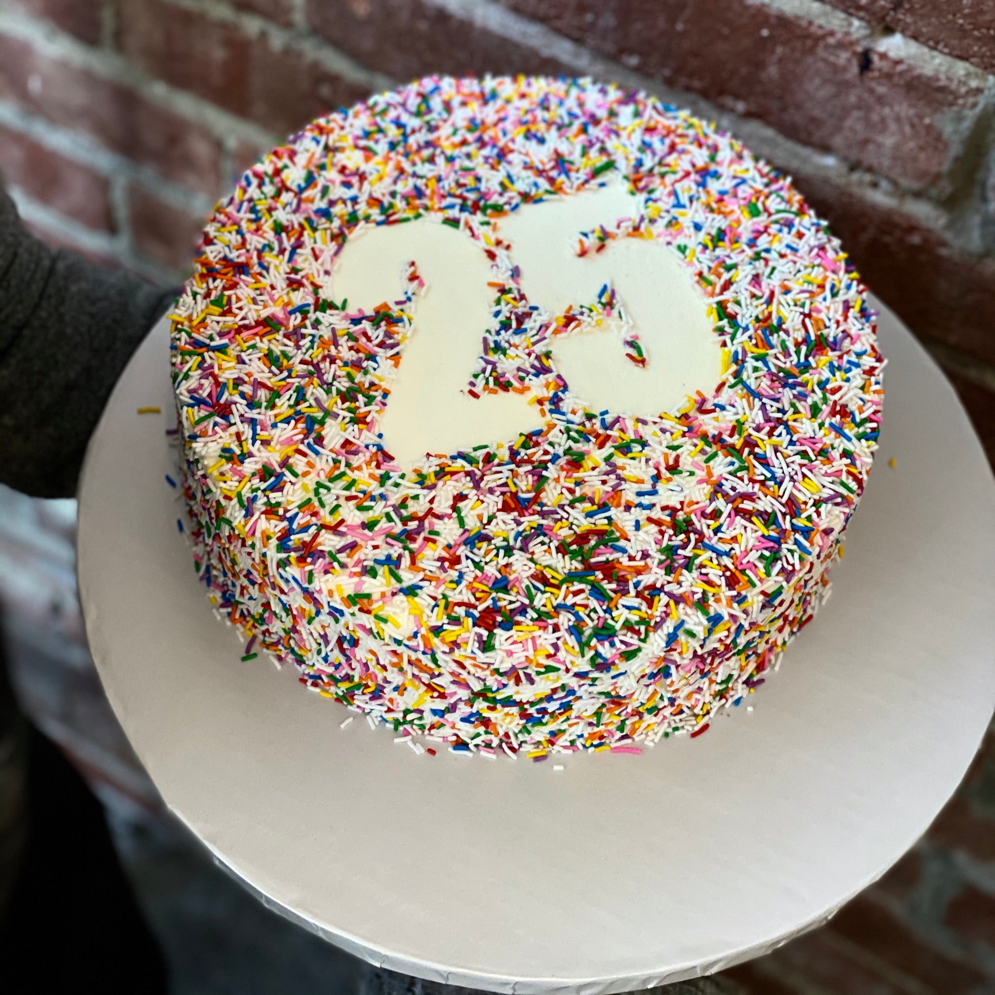 White cake with colourful sprinkles and white number