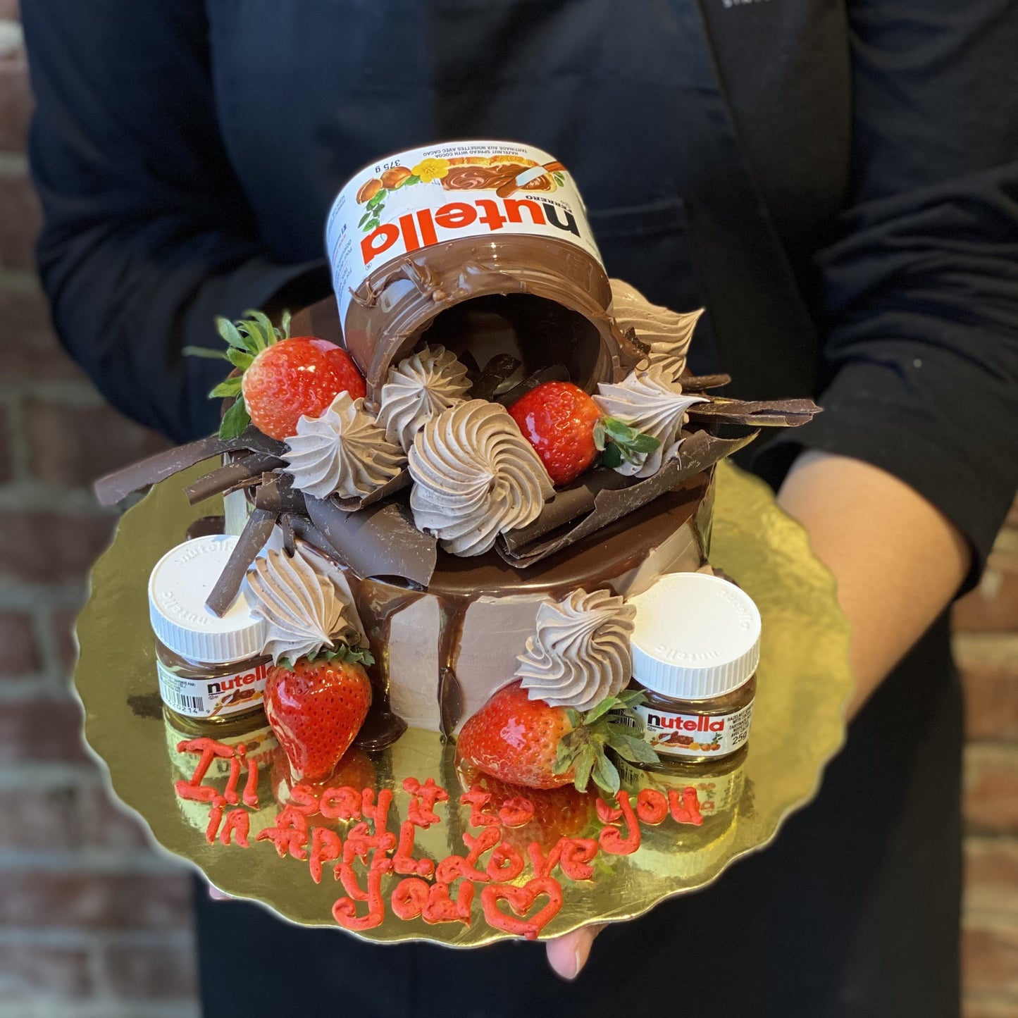 Chocolate cake with Nutella jars on top and fresh strawberries